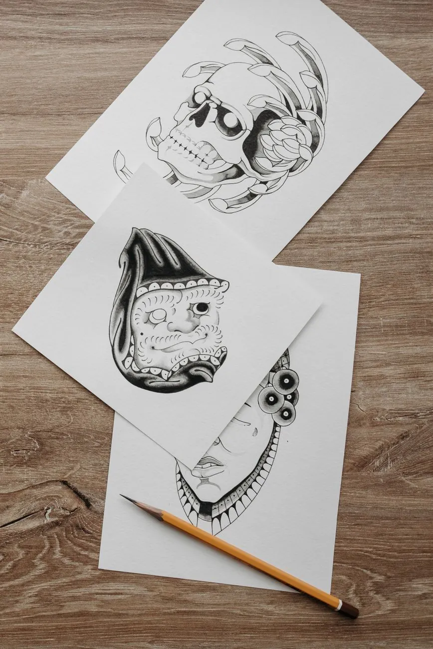 Ink game character sketches spread across a wooden desk beside a pencil