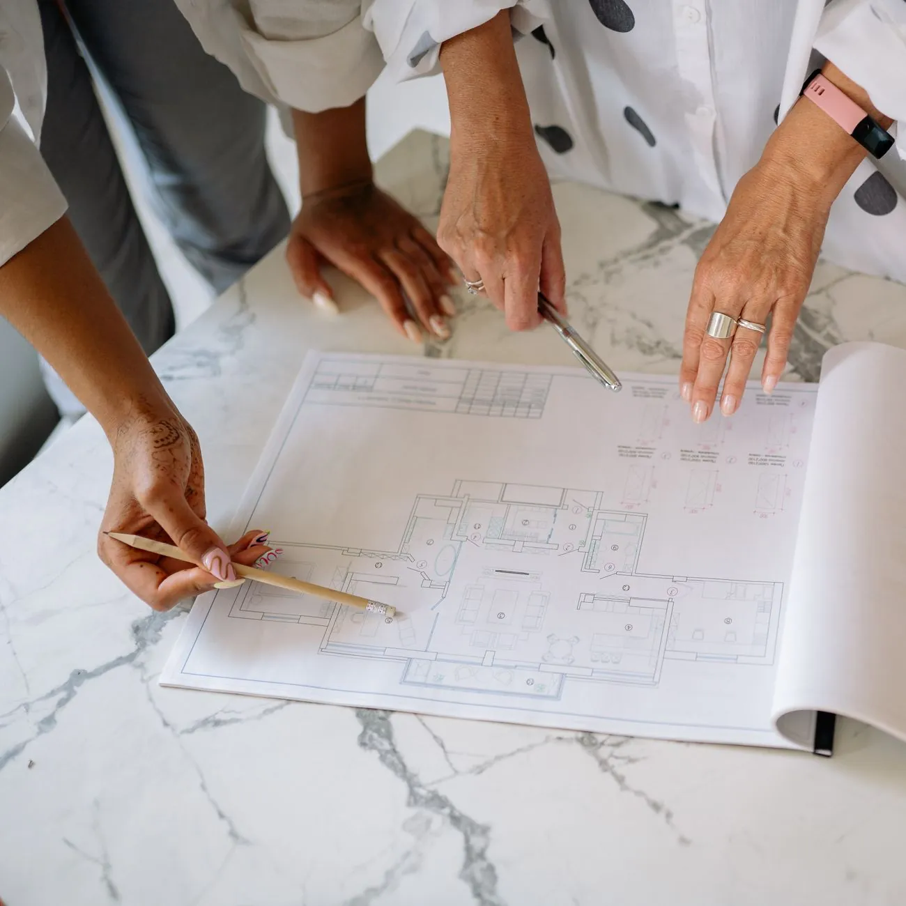 Two people reviewing hand-drawn level layouts and design plans with pencils